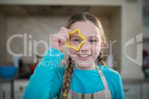 Girl holding cookie cutter on her eyes