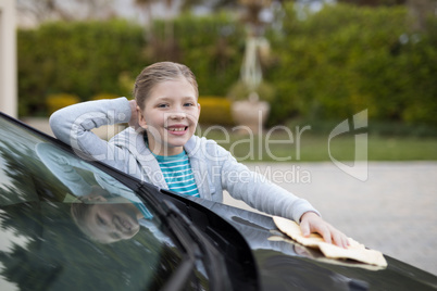 Teenage girl washing a car on a sunny day