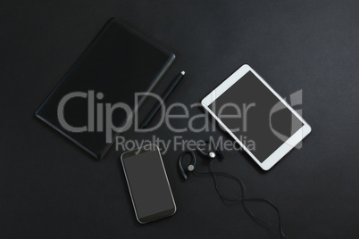 Mobile phone, graphic tablet, headphones, pen and digital tablet on black background