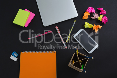 Laptop, mobile phone and stationery on black background