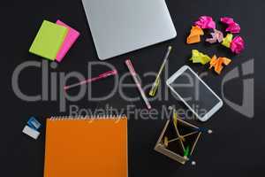 Laptop, mobile phone and stationery on black background
