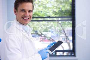 Portrait of doctor using tablet while standing against wall