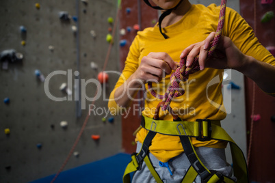 Midsection of female athlete tying rope in health club