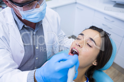 Dentist holding tools while treating woman at medical clinic