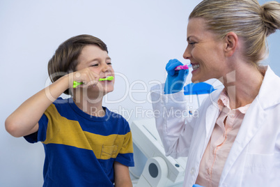 Happy dentist and boy brushing teeth against wall