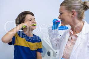 Happy dentist and boy brushing teeth against wall