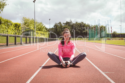 Woman performing stretching exercise on a race track