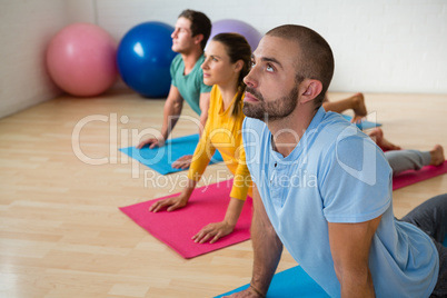 Instructor guiding students in practicing cobra pose at yoga studio