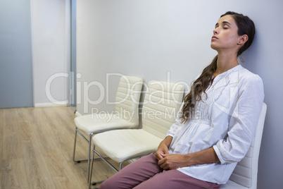 Sad patient with eyes closed sitting on chair at hospital