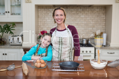 Smiling mother and daughter standing in the kitchen