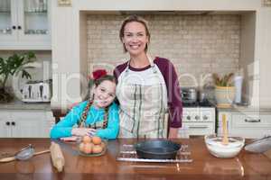 Smiling mother and daughter standing in the kitchen