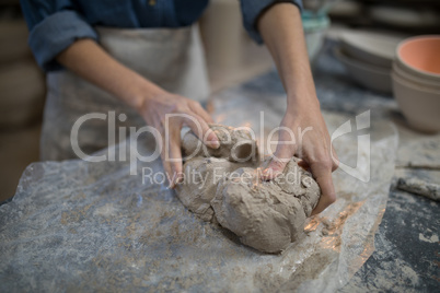Mid section of female potter molding a clay