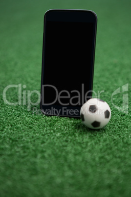 Football and mobile phone on artificial grass