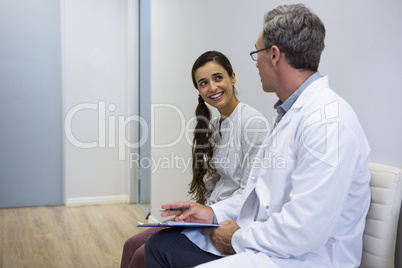 Dentist and smiling patient discussing while sitting on sofa