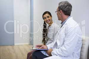 Dentist and smiling patient discussing while sitting on sofa