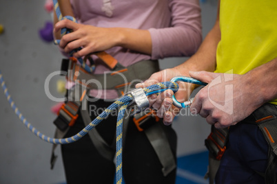 Midsection of athletes adjusting safety harness in club
