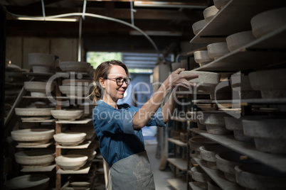 Female potter placing bowl in shelf