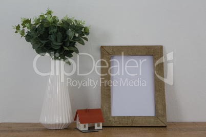 Picture frame, vase and house model on wooden table