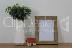 Picture frame, vase and house model on wooden table