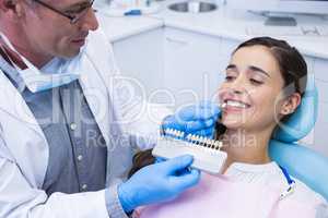 Dentist holding equipment while examining woman at clinic