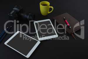 Digital tablet, black coffee, camera, organizer and pen on black background