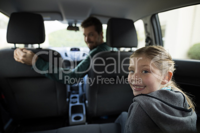 Teenage girl sitting in the back seat while woman driving a car