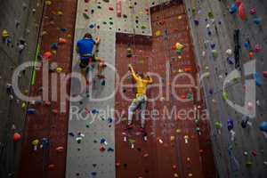 Rear view of athletes climbing wall in health club