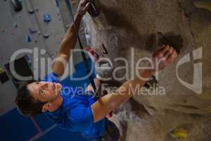High angle view of athlete climbing wall in fitness studio