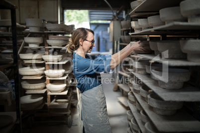 Female potter placing bowl in shelf