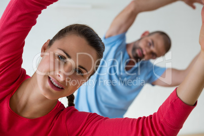 Portrait of female student exercising with instructor in health club