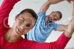 Portrait of female student exercising with instructor in health club