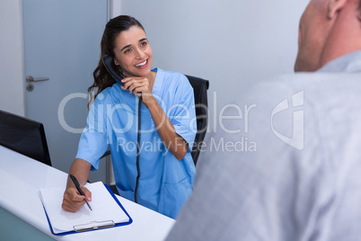 Happy doctor talking on phone while looking at patient