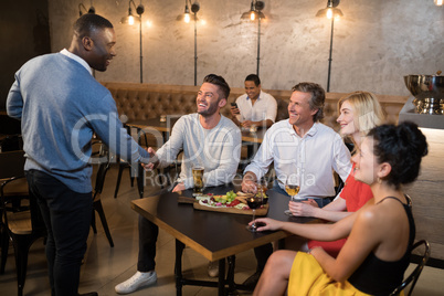 Friends shaking hands while having meal