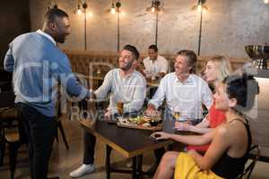 Friends shaking hands while having meal