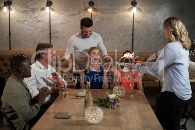 Woman receiving surprise birthday cake from her friends