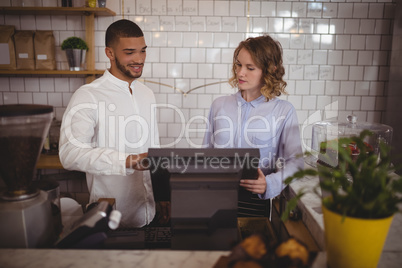 Male owner with waitress using computer at counter