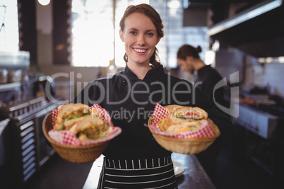 Portrait of smiling waitress serving fresh burgers at coffee shop