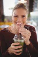 Portrait of beautiful young woman drinking from disposable glass