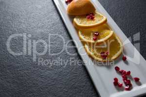 Slice of orange with pomegranate seeds in tray