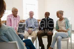 Woman holding tablet computer while discussing with senior adults