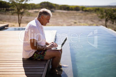 Man using laptop near poolside