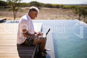 Man using laptop near poolside