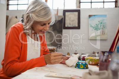 Senior woman painting bowl in drawing class