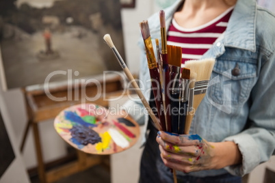 Woman holding various brushes in drawing class