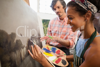 Man assisting woman in painting