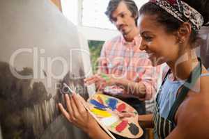 Man assisting woman in painting