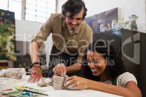 Man assisting woman in molding clay