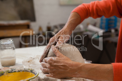 Mid-section of senior woman molding clay