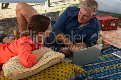 Man with woman using laptop in tent