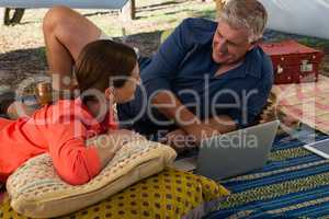 Man with woman using laptop in tent
